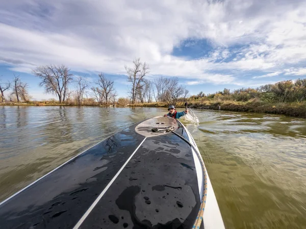 Homme nageant derrière paddleboard — Photo