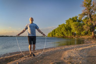 senior man jumping rope on a beach clipart