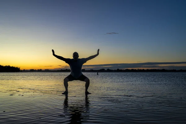 Silhouette lever de soleil d'un homme sur un lac — Photo