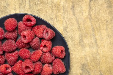 siyah plaka üzerinde taze kırmızı ahududu