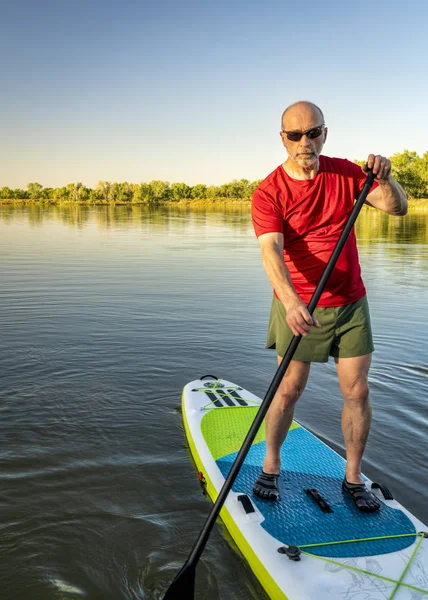 Adulto mayor en el paddleboard inflable del stand para arriba —  Fotos de Stock