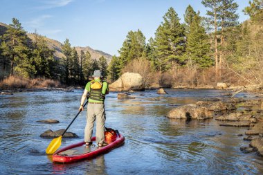 stand up paddling on mountain river clipart