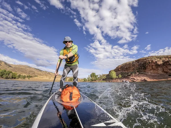 Senior man peddelen een stand up paddleboard — Stockfoto