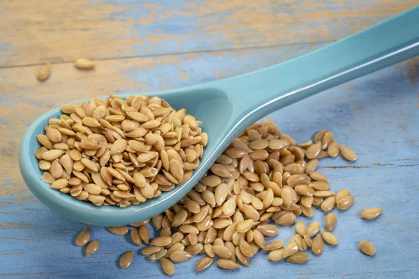 Golden flax seeds on stoneware spoon — Stock Photo, Image
