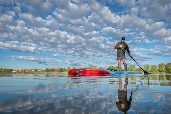 コロラド州の穏やかな湖でスタンドアップパドルボードを漕ぐシニア男性 アクションカメラからの低角度ビュー レクリエーション トレーニング フィットネスの概念 — ストック写真