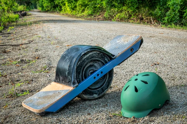 One-wheeled electric skateboard with a helmet on wet and muddy Steamboat Trail converted from abandoned railroad running along Missouri River between Brownville and Nebraska City, NE.