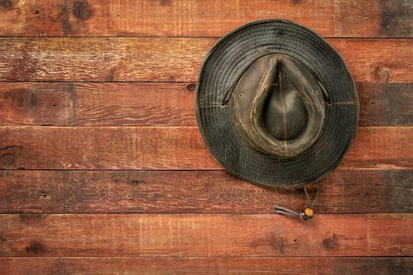 コピースペースのある素朴な赤い納屋の木製の壁にぶら下がっている後ろのオイルスキンの帽子を風化 — ストック写真