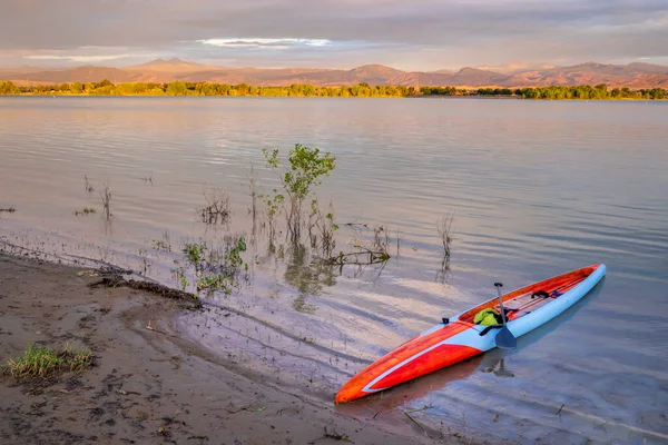 位于科罗拉多州北部的博伊德湖和落基山脉前缘的日出 在海岸上有一个长长的立式滑板 准备划桨 — 图库照片