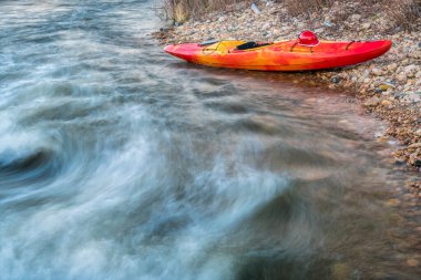 Bir dağ nehri kıyısında miğferli beyaz su kayağı. Fort Collins, Colorado 'daki Poudre Nehri.
