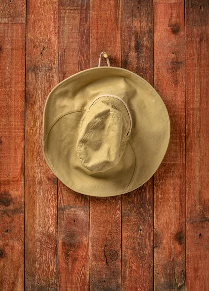 hiking sun hat  hanging on a weathered wooden barn wall, copy space