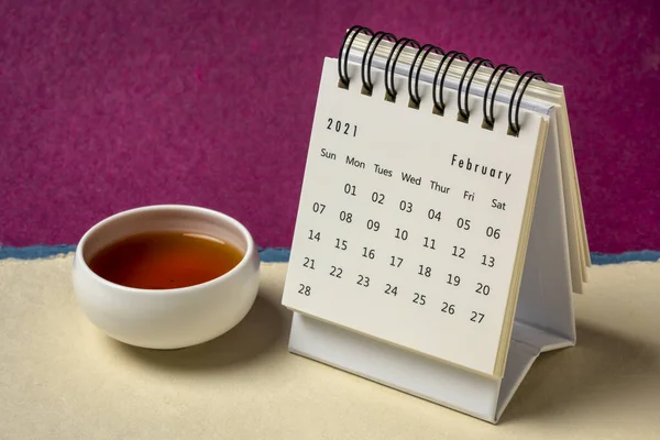 2021年2月 与色彩艳丽的手工纸制日历相对照的螺旋式桌面日历 附带一杯茶 一个季节 一个时间和一个商业概念 — 图库照片