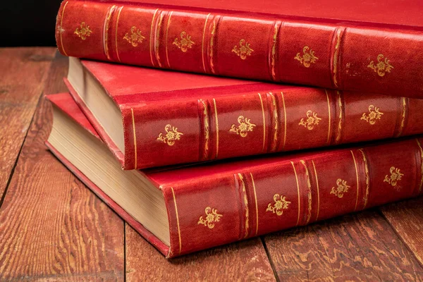 Stos Zabytkowych Książek Czerwoną Skórą Spin Złote Ozdoby Rustykalnym Drewnianym — Zdjęcie stockowe