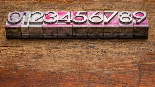 0から9までの数ヴィンテージ コピースペースのある素朴な風化した木に対してインクを印刷することによって染色された重い金属の活版印刷タイプ — ストック写真