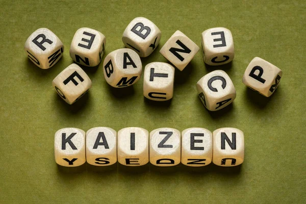 kaizen word abstract in wooden letter cubes against green handmade paper in green tones,  Japanese continuous improvement and a change for better concept