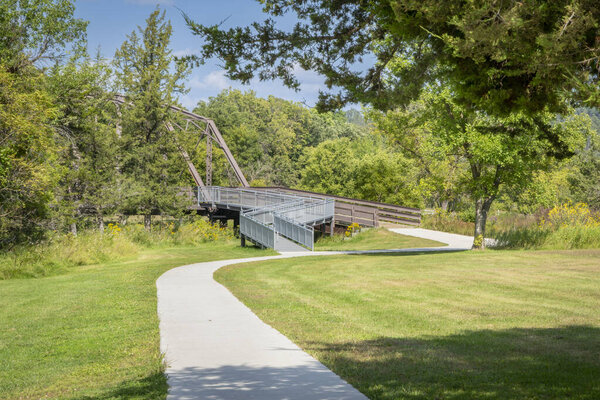 тропа, доступная дорожка и мост через реку Ниобрара, ведущие к популярному водопаду в парке Смит Фоллс, штат Небраска, в конце лета