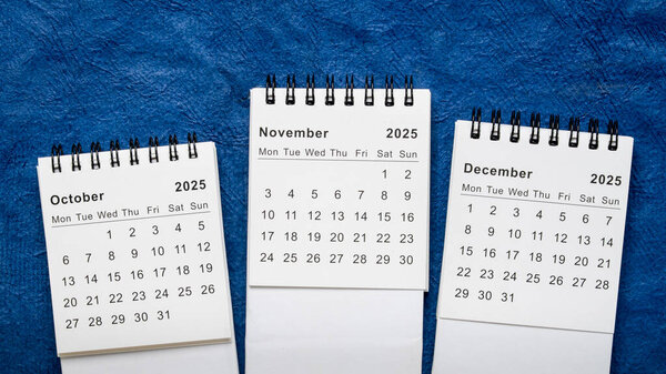 October, November and December 2025 - small spiral desktop calendars, time and business concept
