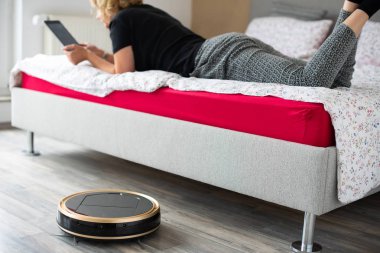 Vakum temizlik robotu ile rahat kadın arka planda okuma