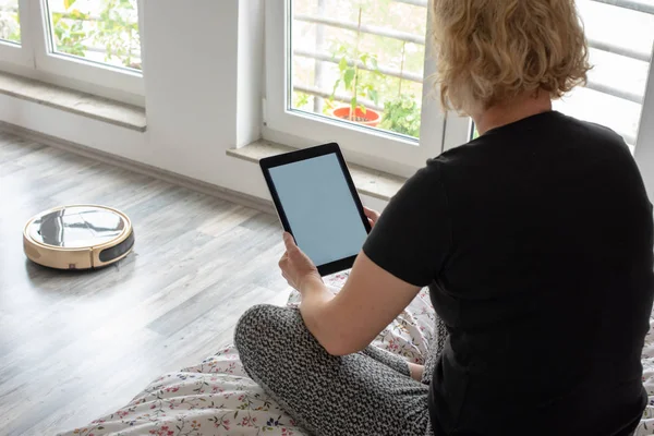 Vacuum cleaning robot with woman reading — Stock Photo, Image