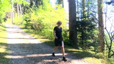 Orta yaşlı kadın yokuş aşağı ormanda yürüyüş