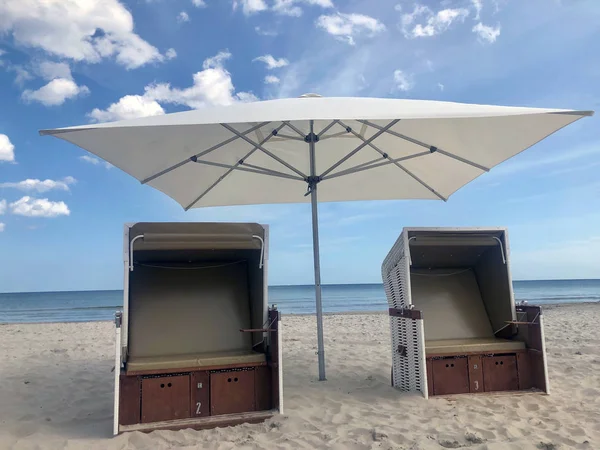 Cadeiras de praia de vime cobertas contra o grande céu nublado — Fotografia de Stock