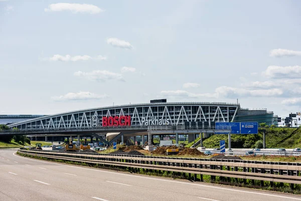 Enormes cartas de Bosch en el aparcamiento del aeropuerto de Stuttgart con la autopista vacía A8 y obras de construcción en primer plano. Bosch es una multinacional alemana de ingeniería y electrónica. . —  Fotos de Stock