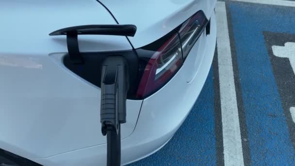 An electric car Tesla Model 3 is recharging the batteries at a public charging station at the airport in Stuttgart, Germany. — Stock Video