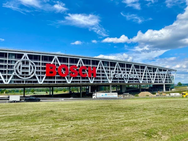 Enormes cartas de Bosch en el aparcamiento del aeropuerto de Stuttgart con la autopista vacía A8 y obras de construcción en primer plano. Bosch es una multinacional alemana de ingeniería y electrónica. . — Foto de Stock