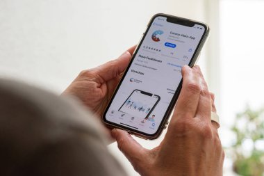 Orta yaşlı bir kadın Apple iPhone 11 Pro 'sunda korona salgınıyla savaşmak için yeni akıllı telefon uygulamasını indirmek üzere. Uygulama Alman hükümetinden geldi ve Robert tarafından geliştirildi.