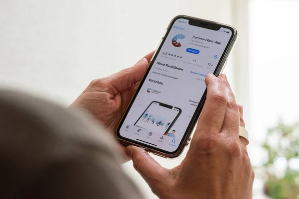 Una mujer de mediana edad está a punto de descargar la nueva aplicación para teléfonos inteligentes para combatir la pandemia de corona en su Apple iPhone 11 Pro. La aplicación se encarga del gobierno alemán y desarrollado por el Robert —  Fotos de Stock