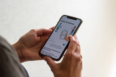 Orta yaşlı bir kadın Apple iPhone 11 Pro 'sunda Corona salgınıyla savaşmak için yeni akıllı telefon uygulamasını kullanıyor. Uygulama Alman hükümetinden Robert Koch tarafından geliştirildi.