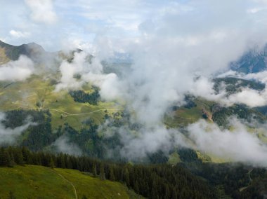 Avusturya 'nın Alpler bölgesindeki Saalbach kayak bölgesinde Kohlmais tepesindeki güzel dağ manzarası güneşli bir yaz gününde bulutların altında.