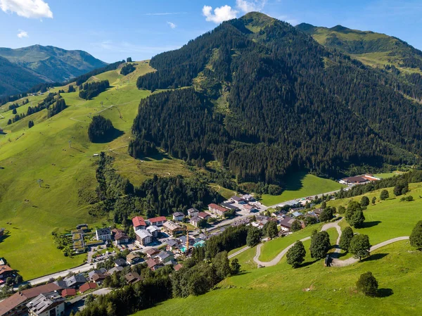 Letecký pohled na vesnici Hinterglemm a hory s lyžařskými vleky v lyžařské oblasti Saalbach-Hinterglemm v Rakousku za krásného letního dne — Stock fotografie