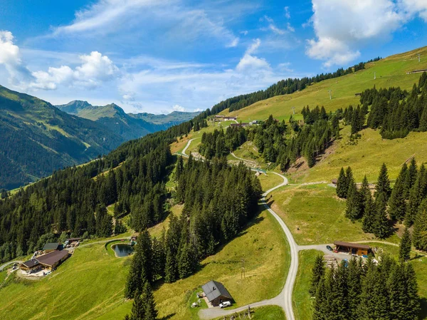 Uitzicht vanuit de lucht op gezellige hutten en bergen in het skigebied Hinterglemm in de Alpen in Oostenrijk op een zonnige zomerdag — Stockfoto