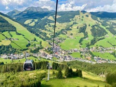 Saalbach köyündeki hava manzarası ve Avusturya 'daki Saalbach-Hinterglemm kayak bölgesindeki dağlar tatil beldeleri, kilise ve diğer tatil beldeleri ile güzel bir yaz günündeydi.