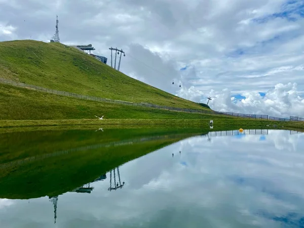Vue sur le réservoir d'eau utilisé pour les canons à neige en hiver dans le domaine skiable de Hinterglemm dans les Alpes autrichiennes par une journée d'été avec un grand panorama de montagne en arrière-plan — Photo