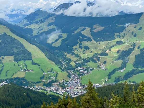 Vista aérea del pueblo de Saalbach y las montañas en la región de esquí de Saalbach-Hinterglemm en Austria en un hermoso día de verano desde el teleférico en el pueblo con cambios de vacaciones, la iglesia y otros — Foto de Stock