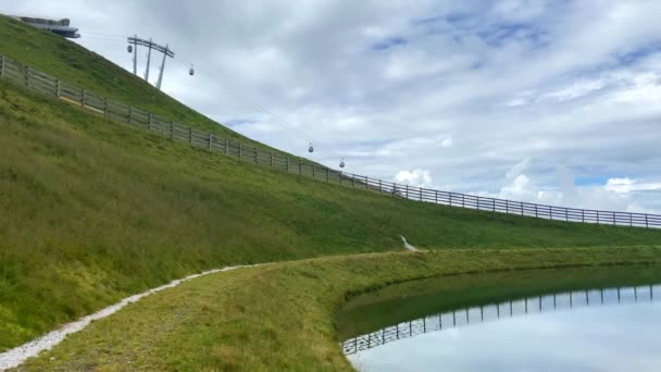 オーストリアのヒンテルグレムのスキー地域で冬に雪の大砲のために使用される貯水池と山の風景の上に表示背景にケーブルカーと夏の日にアルプス — ストック動画