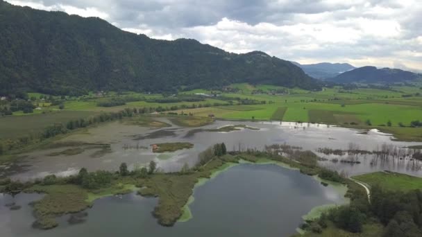 Vista aérea en los extremos superiores del lago Ossiacher en Carintia, Austria, con su páramo y pantanos en un día de verano con gran paisaje nublado — Vídeos de Stock