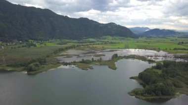 Avusturya, Carinthia 'daki Ossiacher Gölü' nün üst uçlarındaki hava manzarası. Büyük bulutlu bir yaz gününde bataklık ve bataklıklarıyla.