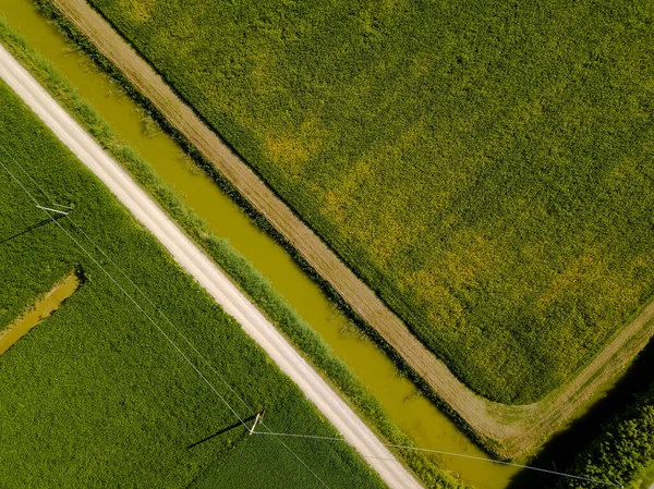 Yukarıdan insansız hava aracı kullanılarak görülebildiği üzere, dereleri, elektrik hatları ve geometrik şekildeki toprak izleriyle tarımsal alanların havadan görüntüsü — Stok fotoğraf