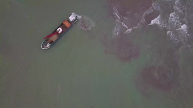 Kirli bir su yolundaki tortu ve çamuru nehir yatağından temizleyen, derinleştiren ve kaldıran bir kanal üzerinde çalışan kazıcı taramasının havadan aşağı görüntüsü