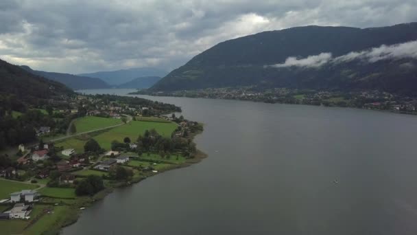 Vista aérea en los extremos inferiores del lago Ossiacher en Carintia, Austria en un día de verano con gran paisaje nublado — Vídeos de Stock