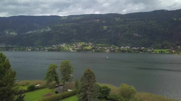 Luftaufnahme vom Ossiacher See in Kärnten, Österreich mit einem Segelboot an einem Sommertag mit toller Wolkenlandschaft — Stockvideo