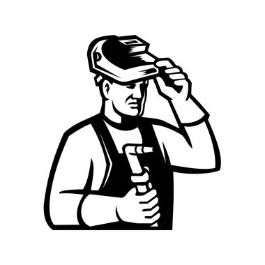 Bir gaz kaynakçısının başındaki maskot ressamı güneşliği kaldırırken ve yan taraftan izole edilmiş siyah beyaz arka planda oksoetilen kaynak meşalesi tutarken görülüyor..