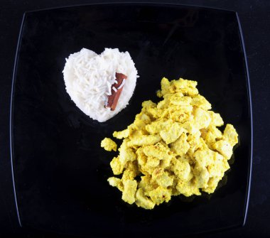 Köri tavuk ile basmati pirinç siyah plaka, yatay görüntü yansıtan üzerinde kalp şeklinde