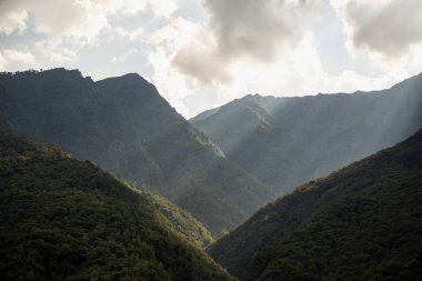 Güneş bulutlar arasında dağları aydınlatıyor, yatay görüntü