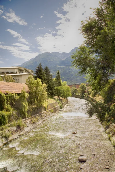 River in between houses and trees, vertical image