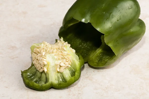 Water Drops On Green Pepper Sitting On Tile Cutting Board With Top Cut Off And Seeds Showing