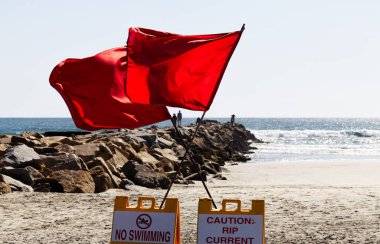 Okyanus Kenarı, Kaliforniya, ABD - 08 Nisan 2024: Okyanus ve Mavi Gökyüzü ile Sahilde İki Kırmızı Uyarı Bayrağı