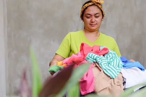 Asiática Jovem dona de casa com uma pilha de roupa nas mãos — Fotografia de Stock